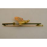 A yellow metal bar brooch stamped 15ct with red, yellow and white metal flying grouse,