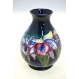 A Moorcroft vase decorated with orchids or other floral designs on the typical mottled ground,