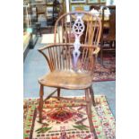 An early 19th century yew wood and elm Windsor elbow chair, the hoop back with pierced wheel splat,