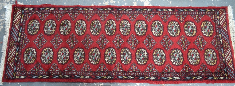 A Pakistan-Afghan design small runner, mid-red ground with two rows of stylised guls,