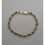 An 18ct yellow gold linked bracelet set with various gems including garnets, sapphires etc,