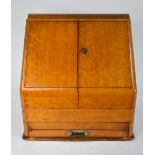 An oak slope front stationary cabinet, having a pair of doors enclosing a fitted interior of niches,