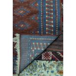 A Persian Bokhara design rug, the field of repeating stylised guls on rust ground,
