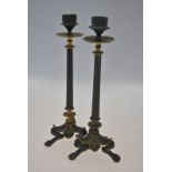 A pair of Empire style gilt and brown patinated metal candlesticks with reeded pillars on foliate