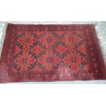 A Belouch rug, the dusky red ground with a lattice work of floral compartments,