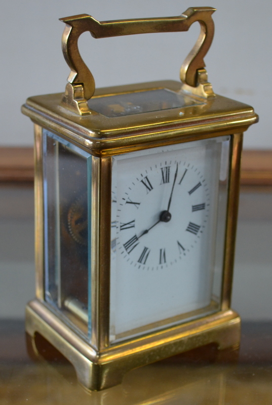 A French brass carriage clock with enamel dial and bevelled glass panels 15 cm high overall