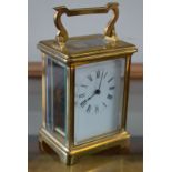 A French brass carriage clock with enamel dial and bevelled glass panels 15 cm high overall