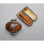 A Far Eastern traditional style oval amber pendant having scrollwork mount set with cabochon