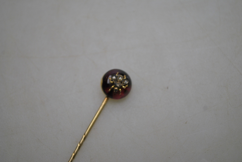 A Victorian stick pin of circular almandine garnet with diamond set bee in centre,