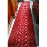 A long narrow Afghan-Turkomen design runner,the red ground with two rows of geometric guls, 4.