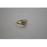 A two-stone brilliant cut diamond crossover ring, white metal set on yellow metal shank, size P,