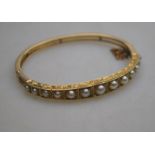A Victorian graduated hinged bangle set with half-pearls having engraved sides,
