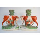 A pair of large Victorian Staffordshire spill vases formed with a cow and calf by a stream,