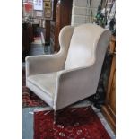 A late Victorian upholstered wing back armchair raised on turned mahogany front legs,