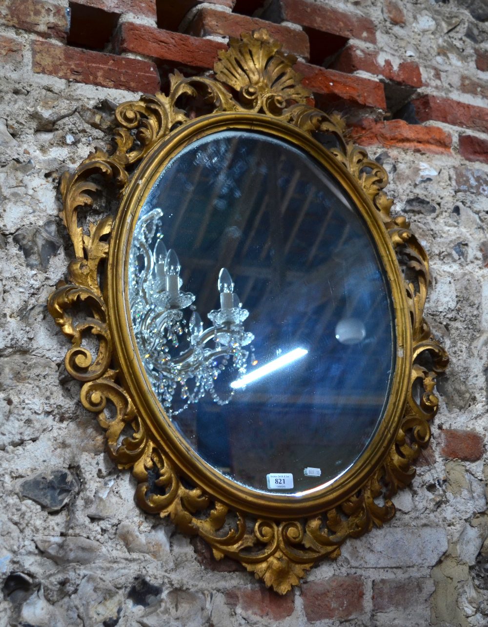A 19th century carved giltwood framed oval mirror surmounted by an open shell,
