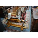 An early 20th century carved wooden rocking horse on turned pillar safety stand,