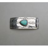 A Navajo hair ornament of rectangular form with central turquoise and stamped design,