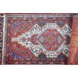 An old Persian Hamadan rug, the mid-red ground centred with a geometric medallion,