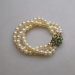 A three-row cultured pearl uniform bracelet having 18ct yellow gold flower style clasp set cabochon