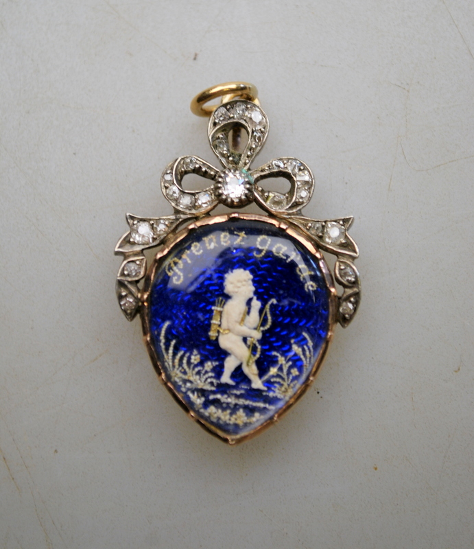 A Georgian heart-shaped pendant featuring Cupid amongst flowers on a blue enamelled background,