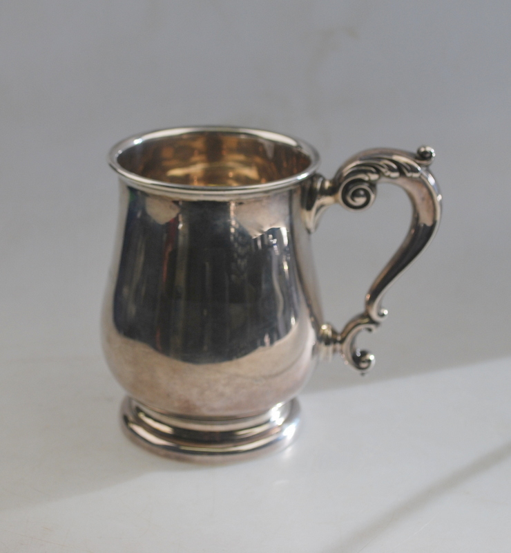 A silver baluster pint mug in the Georgian manner, with scroll handle and moulded foot-rim,