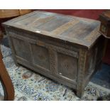 A late 17th/18th century oak coffer, the three panel hinged top over a conforming part carved front,
