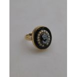 An oval black enamelled ring having agate cameo of flower in centre with half pearl surround,