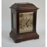 An early 20th century walnut cased eight-day mantel clock with silvered dial incorporating a