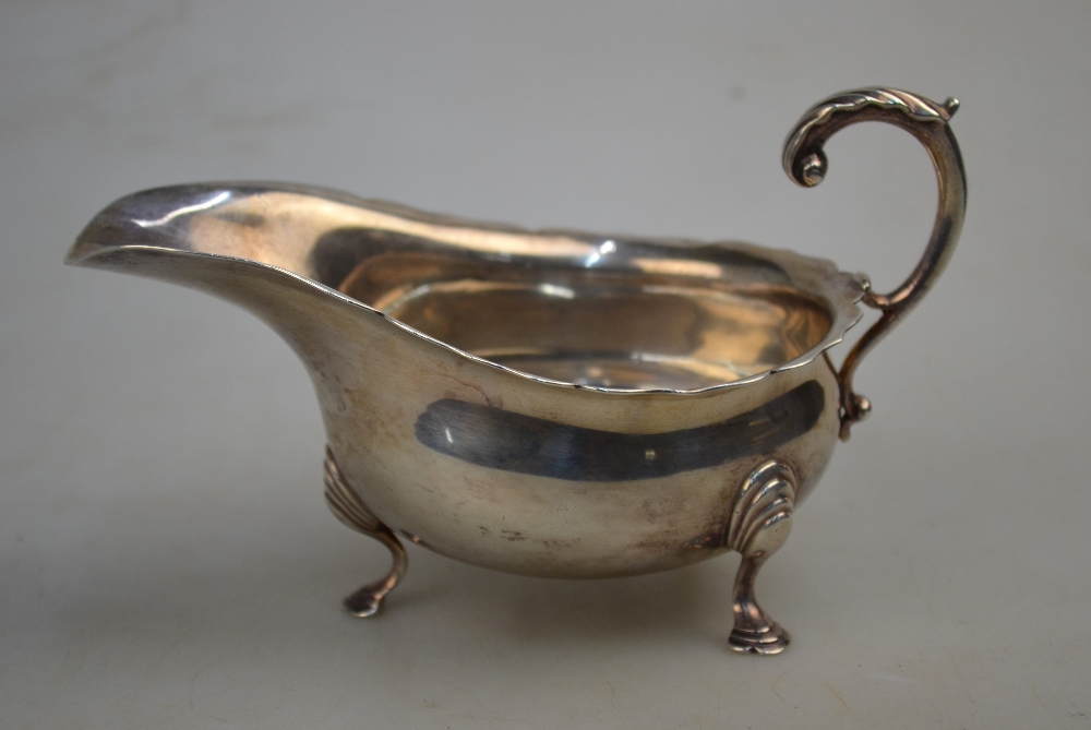 An Edwardian silver sauce boat with cut rim, scroll handle and hoof feet, Haseler Bros.