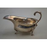 An Edwardian silver sauce boat with cut rim, scroll handle and hoof feet, Haseler Bros.