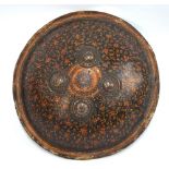 A lacquered wood, circular shield with four circular,