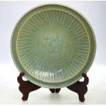 A Ming celadon dish, decorated with a central flower head surrounded by a typical,