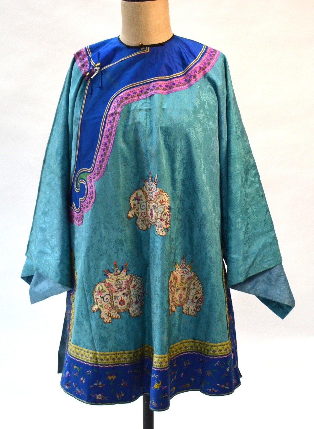 A turquoise-green Chinese coat decorated with peaches and six applique elephants; about 93 cm long,