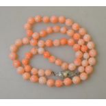 A single row of slightly graduated antique pale coral beads on metal snap stamped silver,