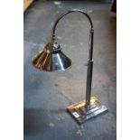 An electroplated desk lamp with conical shade and stepped base