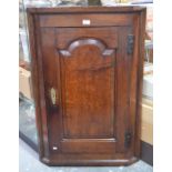 An 18th century oak hanging corner cupboard with fielded arched panel doors enclosing shaped