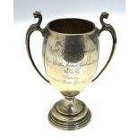 An ovoid silver trophy cup with twin handles surmounted by leopards' heads,