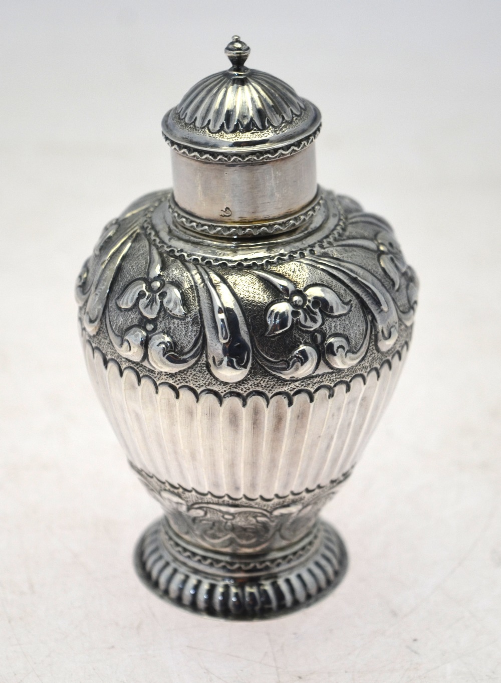 An 18th century Dutch ovoid tea caddy with embossed and chased floral decoration and half-reeding