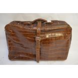 A vintage crocodile suitcase with buckled strap,