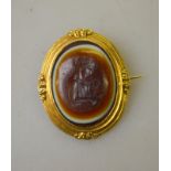 An antique three-coloured agate intaglio brooch featuring a female gazing at a flower,