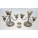 Two Continental white metal three-branch candelabra on weighted circular bases, 16 cm high,