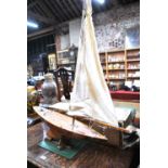 A vintage model pond yacht, the wooden hull with brass weighted fin, c/w alloy mast and cloth sail,