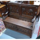 A carved oak box settle with lion form arms