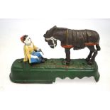 A painted cast iron novelty money box, modelled with a kicking mule and victim,