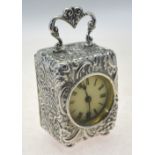 A French white metal desk-clock with hinged loop handle and rococo revival all-over foliate