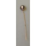 A yellow metal stick pin with enamel classical head surrounded by seed pearls