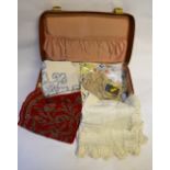 A vintage suitcase containing a collection of table linen to include crocheted edge examples,