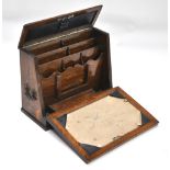 An oak writing box with hinge down front panel revealing stationery interior,