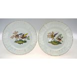 A pair of Berlin moulded plates with reticulated borders painted with fancy birds in branches on a