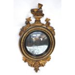 A Regency giltwood & gesso convex mirror surmounted by a snarling dragon, flanked by dolphins,